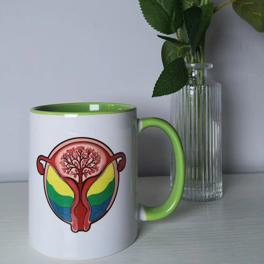 White mug with green handle printed with a blooming womb illustration